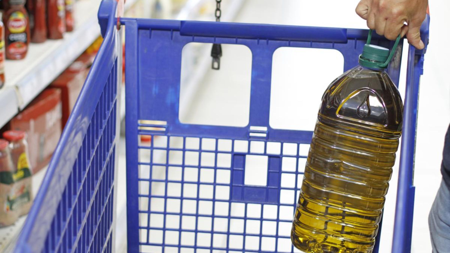 Persona colocando garrafa de aceite en un carro.