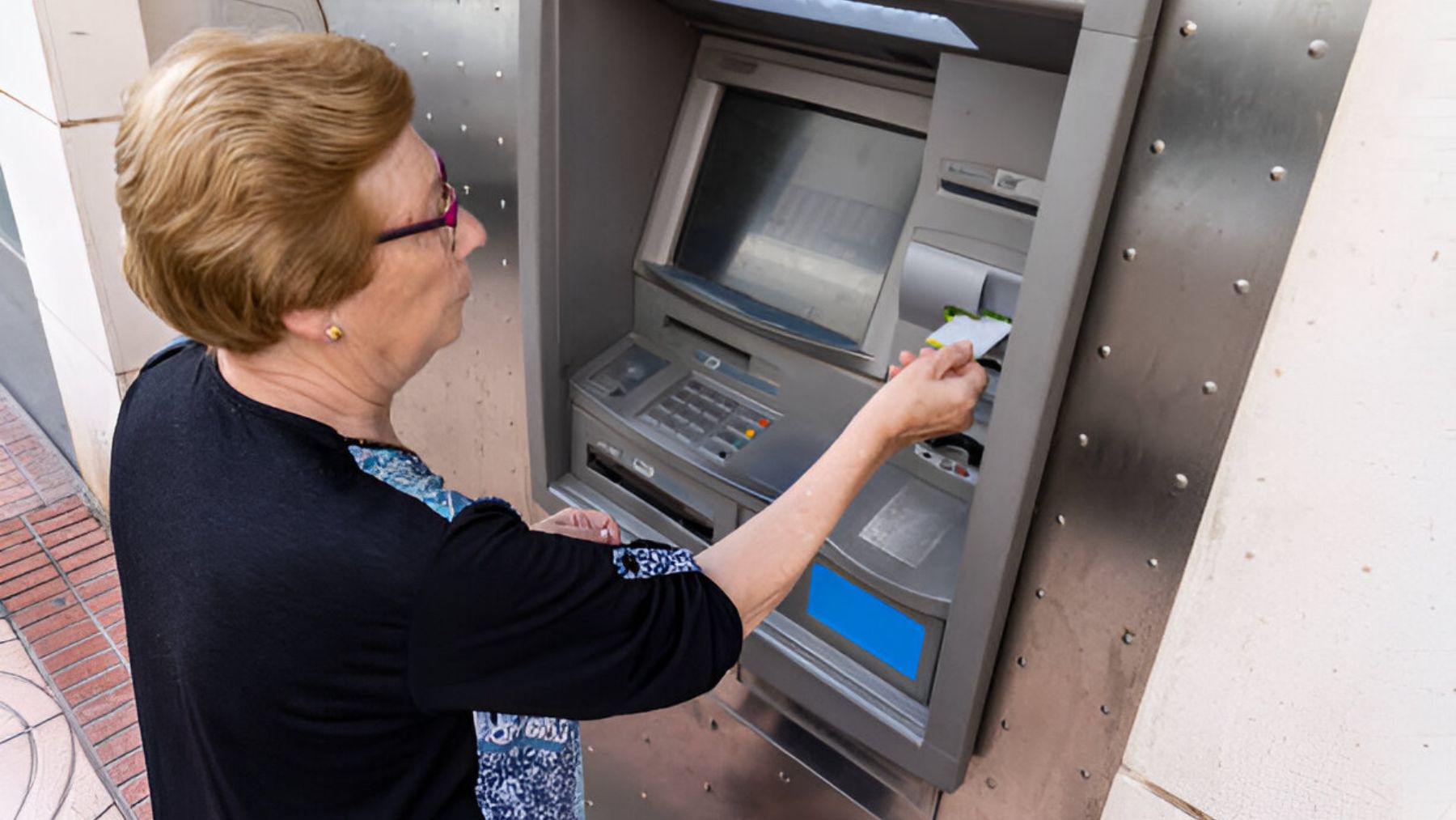 Pensionista sacando dinero de un cajero.