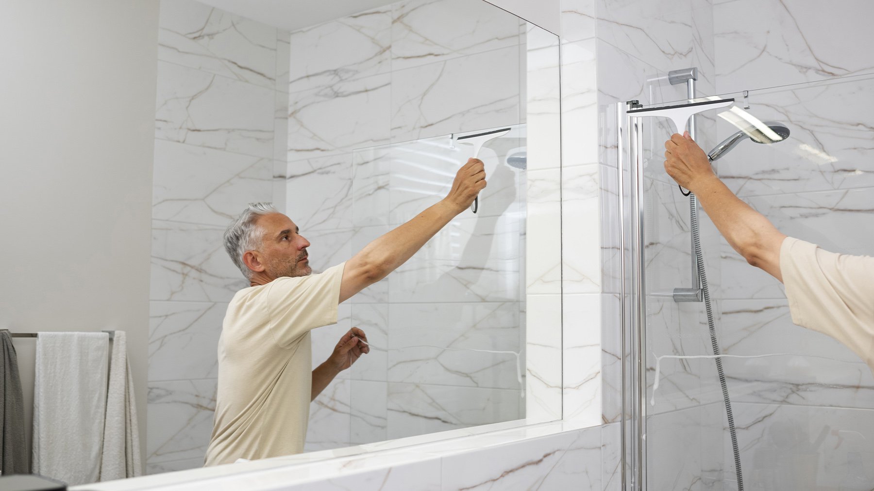 Un hombre limpiando la mampara de baño. Foto: Freepik.