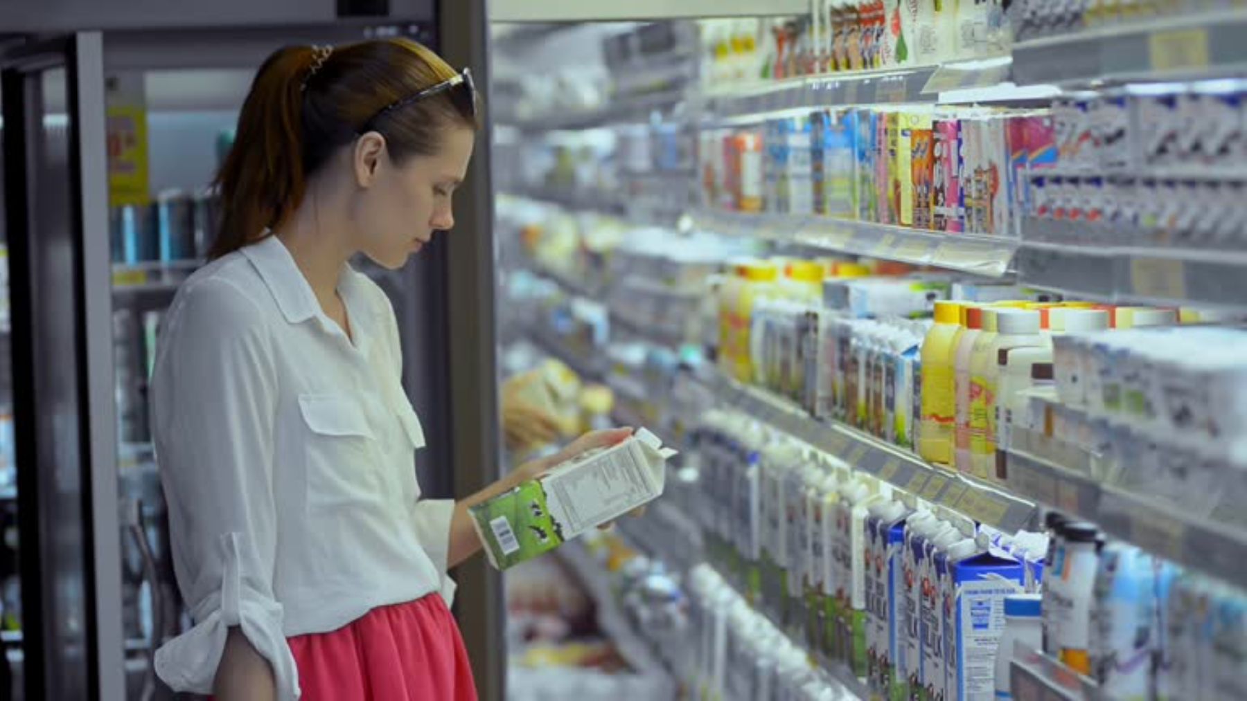 Mujer comprando leche en un supermercado.