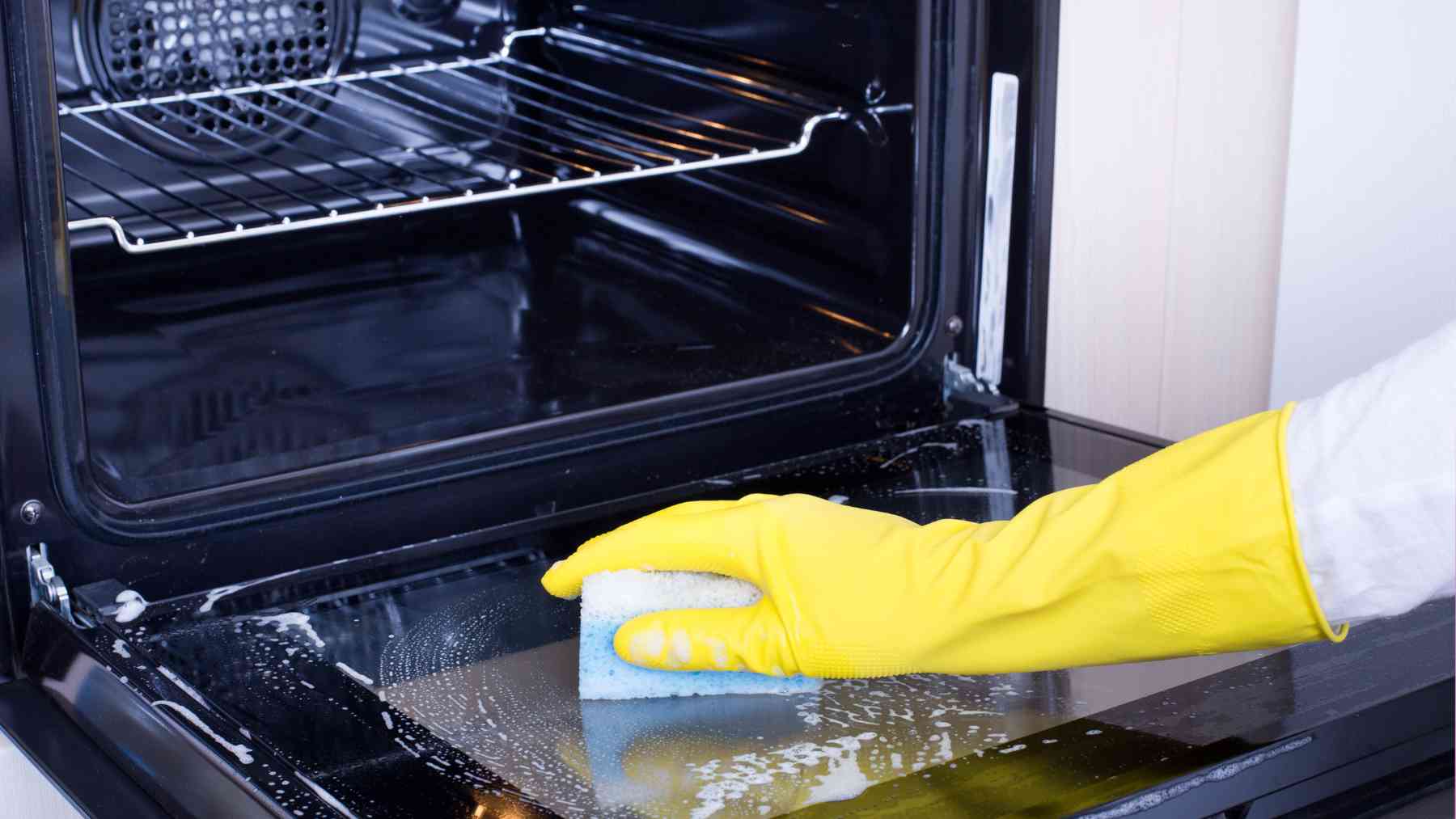 Una persona limpiando el horno.