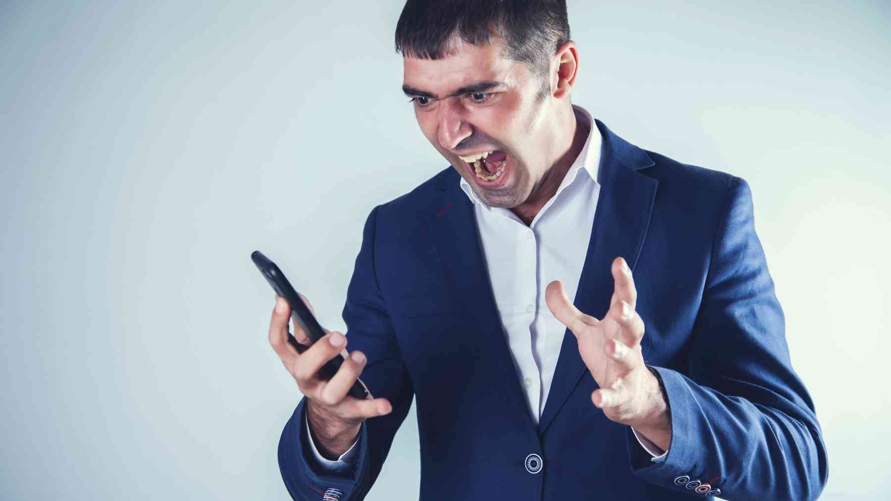 Un hombre enfadado mirando su teléfono.