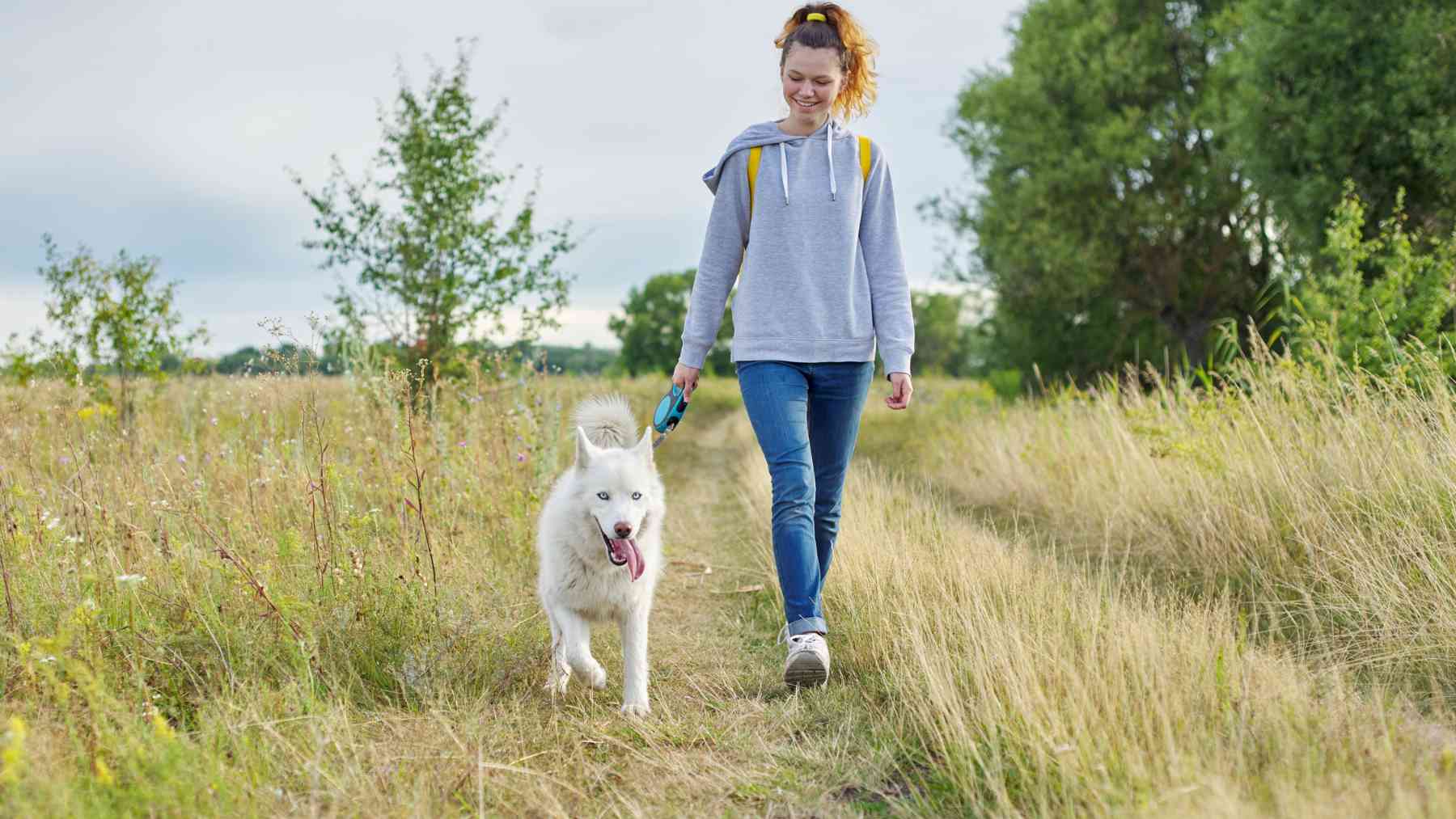 Una joven paseando a su perro.