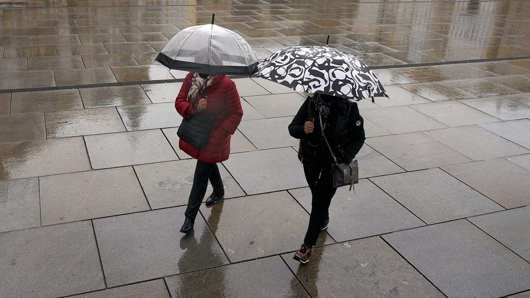 Dos personas se refugian de la lluvia con un paraguas.