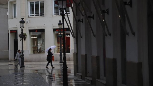 Dos mujeres pasean por Málaga bajo la lluvia.