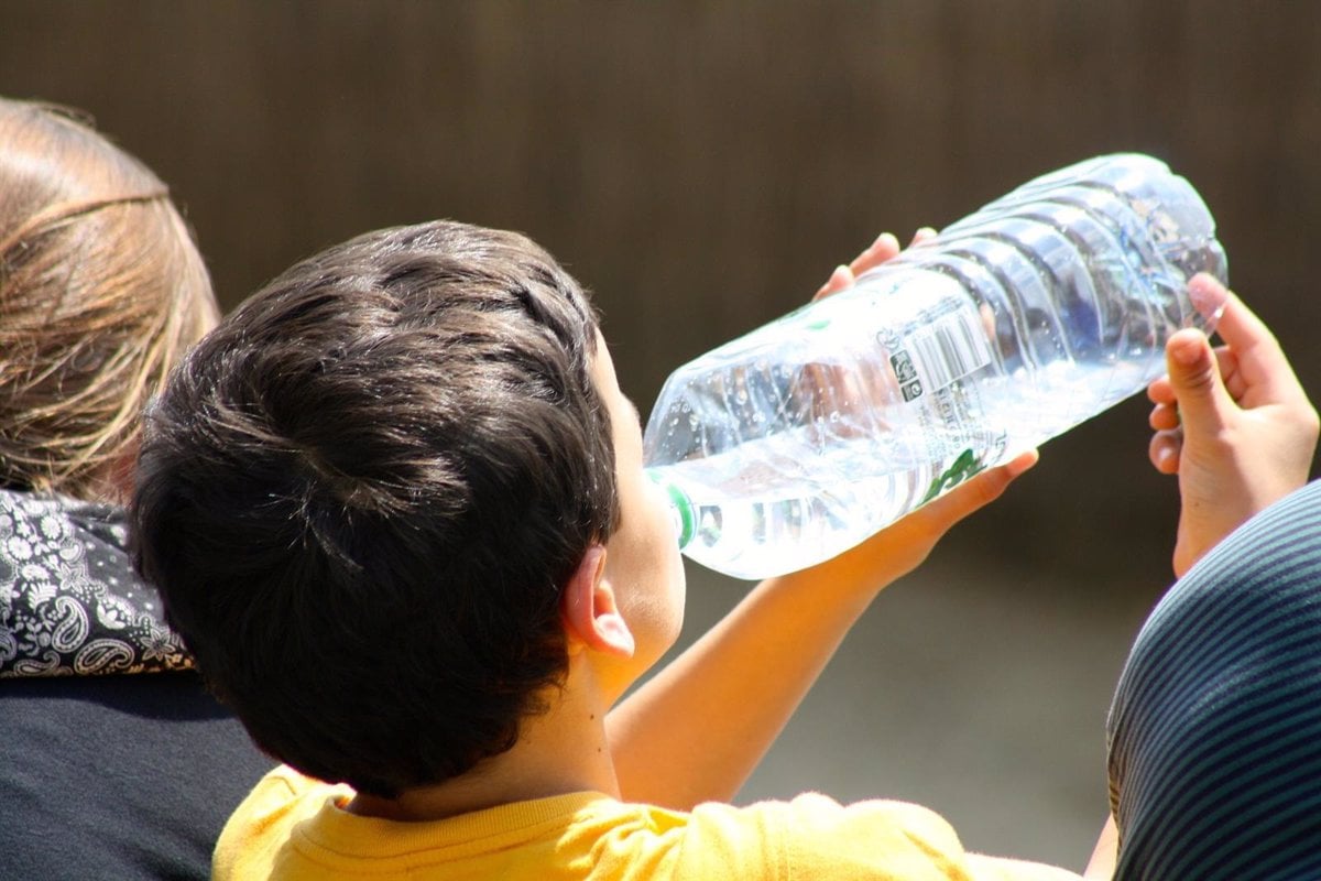 Un niño bebe agua de una botella.