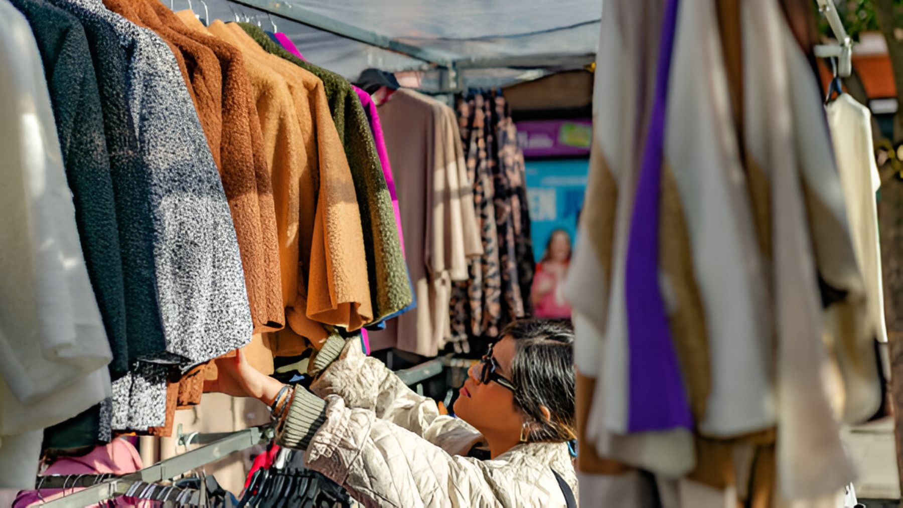 Mujer mirando ropa en un mercadillo.