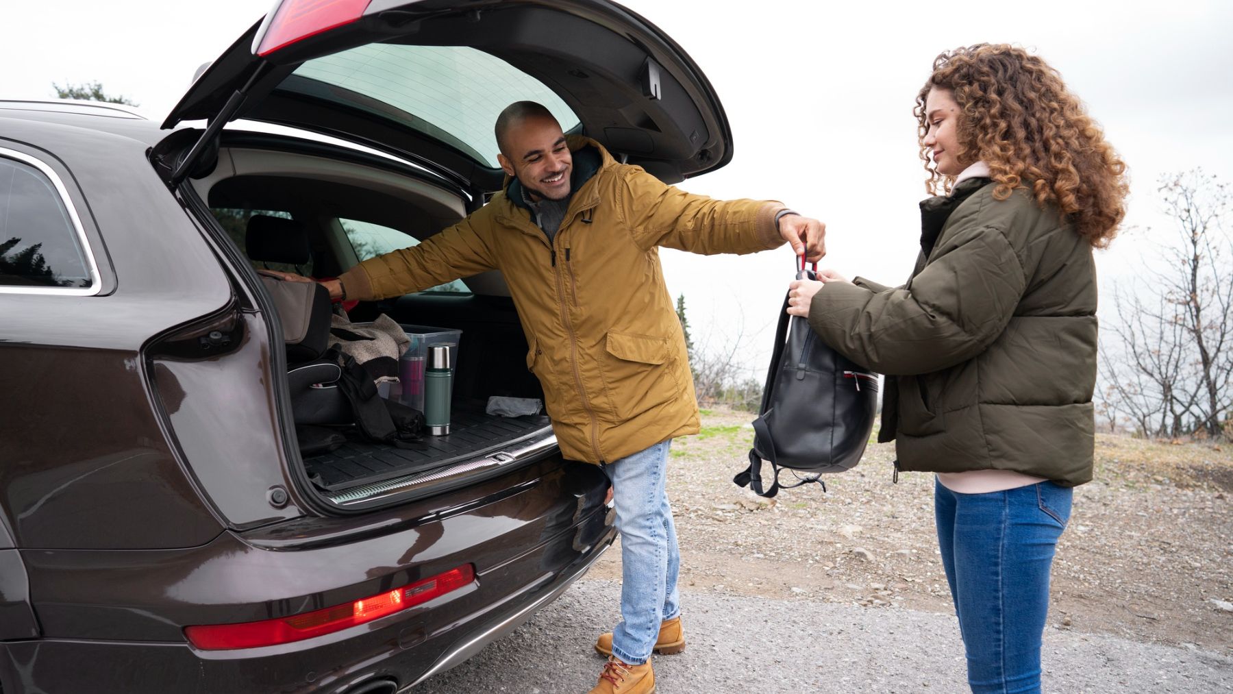 Dos personas sacando objetos del maletero de su coche. Foto: Freepik