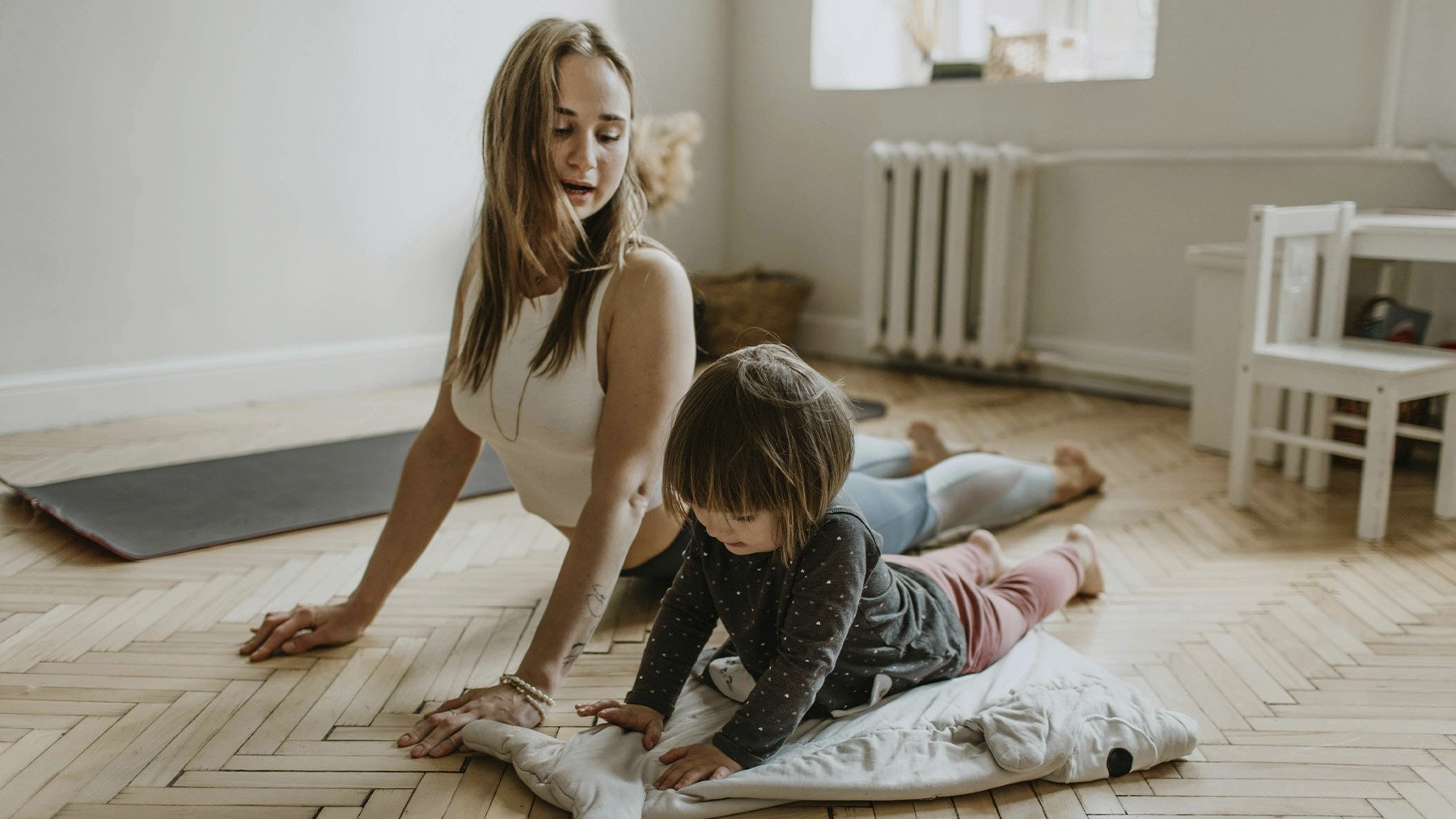 Mujer realizando estiramientos con su hija. Foto: Pexels.