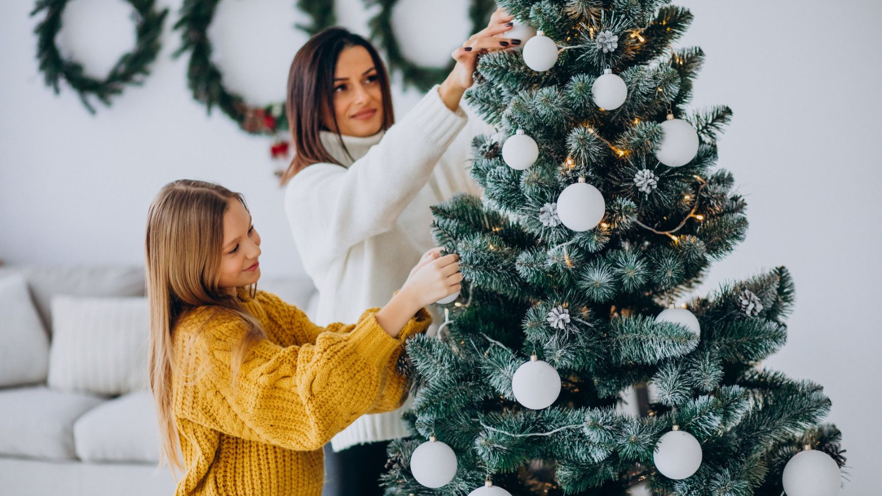 Madre e hija decorando el árbol de Navidad. Foto: Freepik