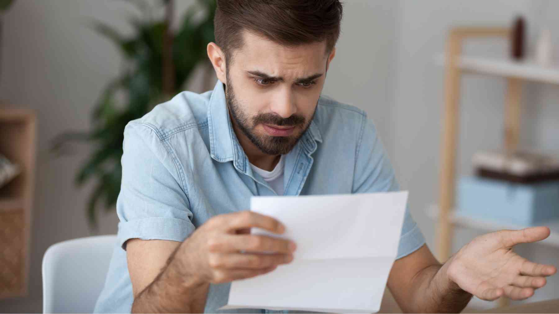 Un hombre leyendo una carta con cara de asombro.