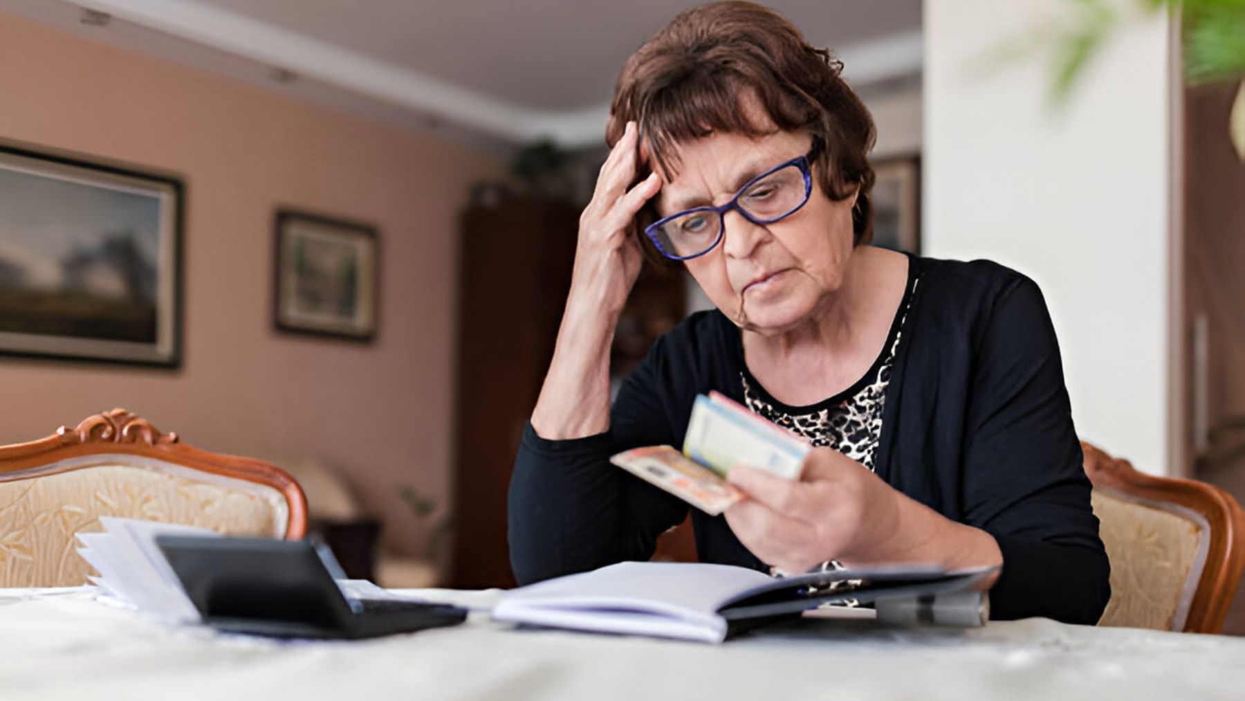 Mujer mayor preocupada con dinero en la mano.