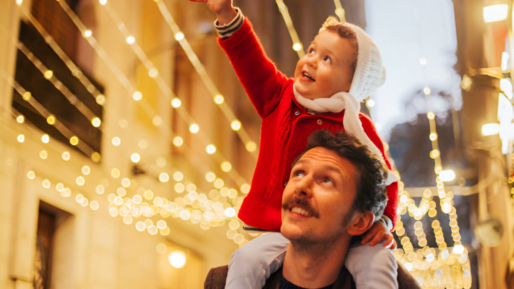 Niño con su padre viendo luces de Navidad.