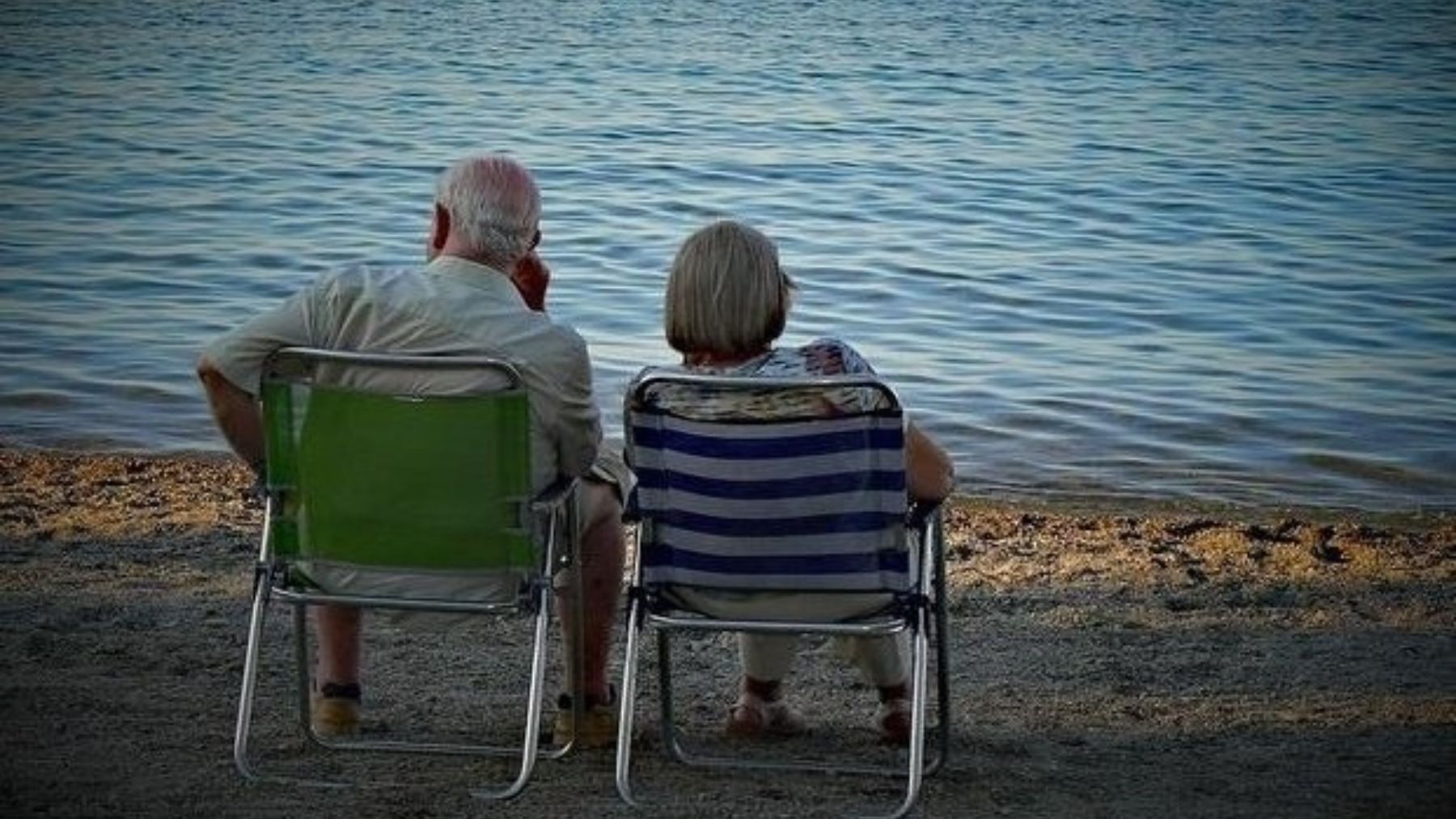 Dos personas mayores sentadas frente al mar. (EP)