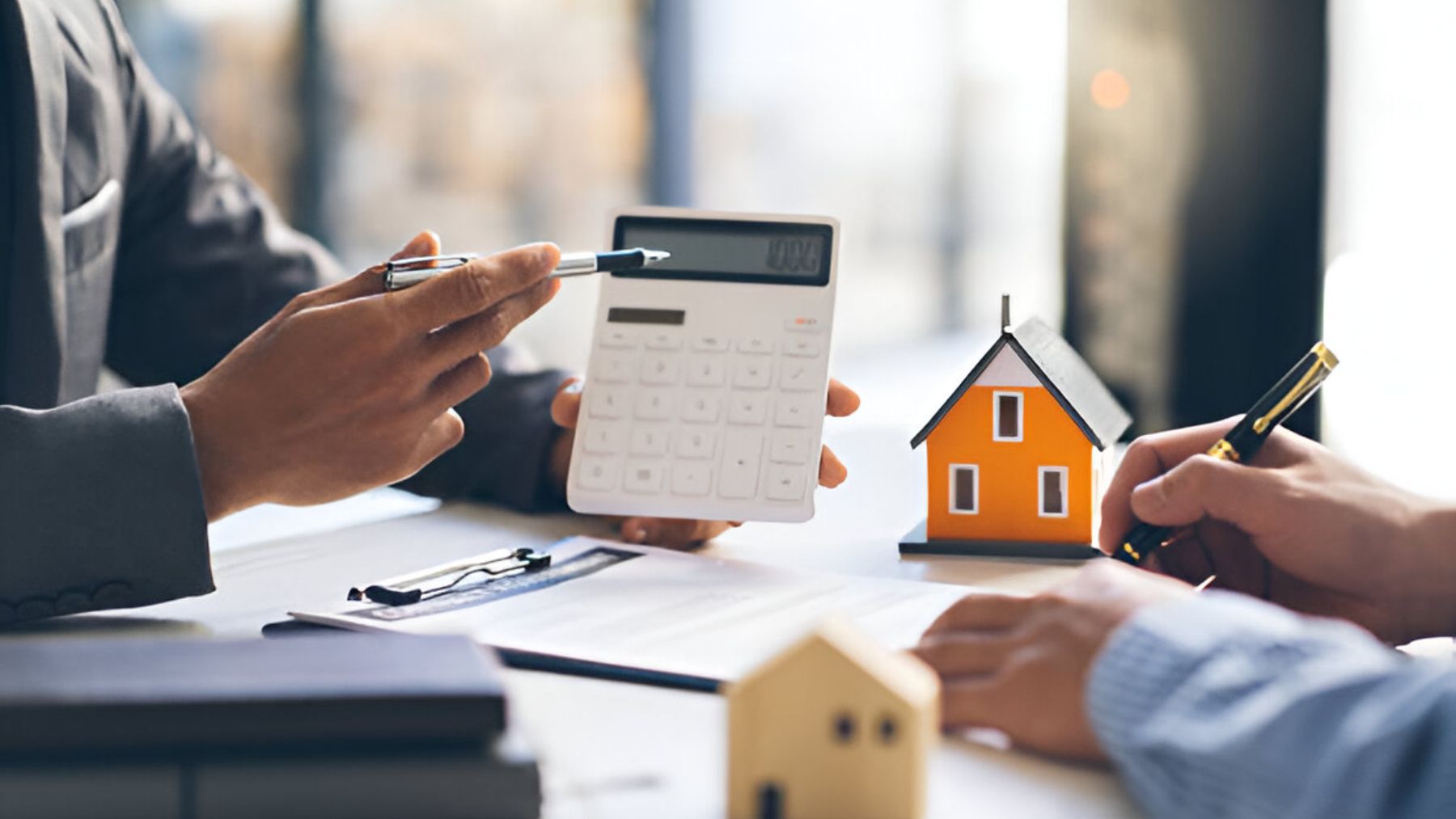 Personas con una calculadora y con una pequeña vivienda.