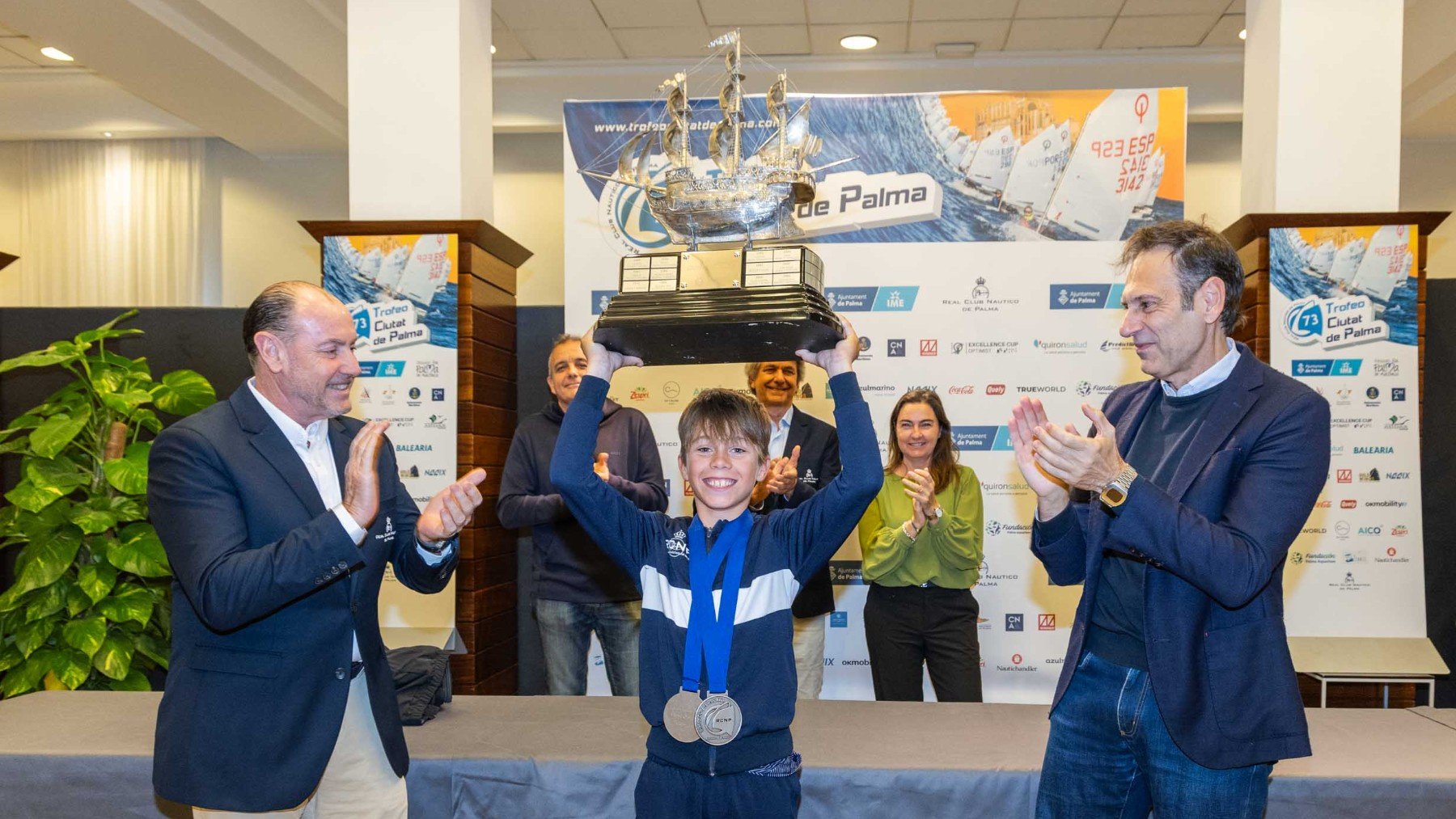 Jan Palou levanta la Carabela de Plata del Trofeo Ciutat de Palma entre Rafael Gil y Pedro Vidal.