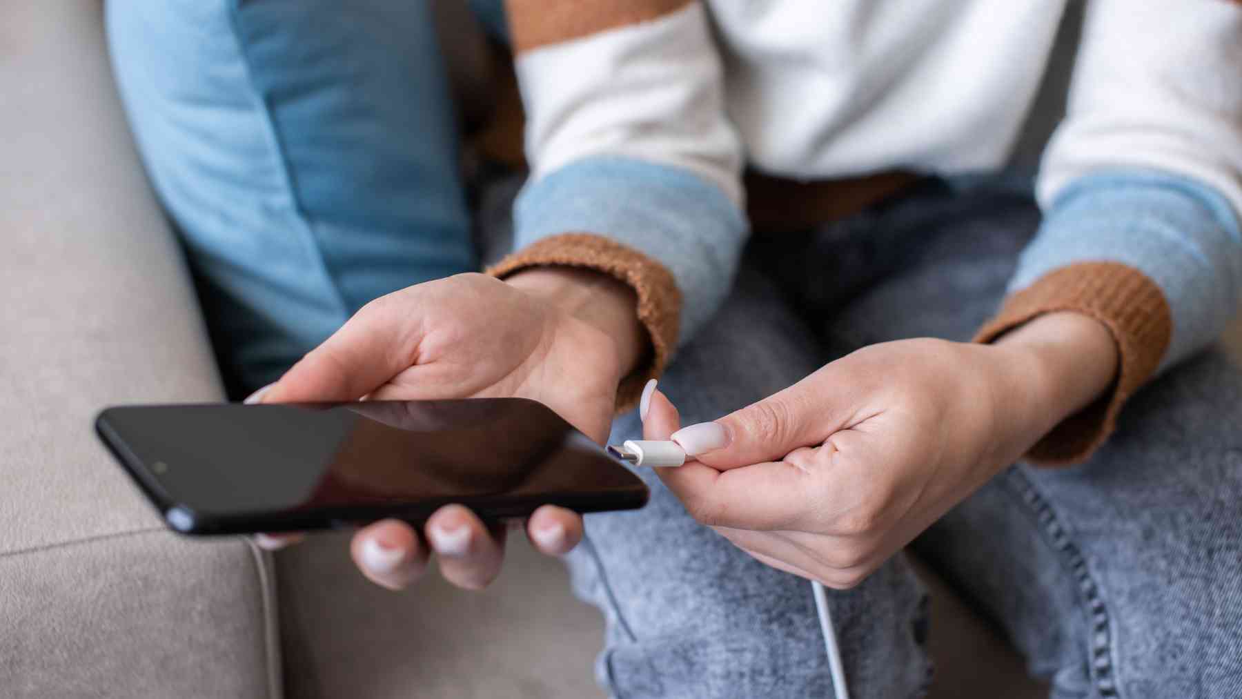 Una persona conectando el cargador al teléfono