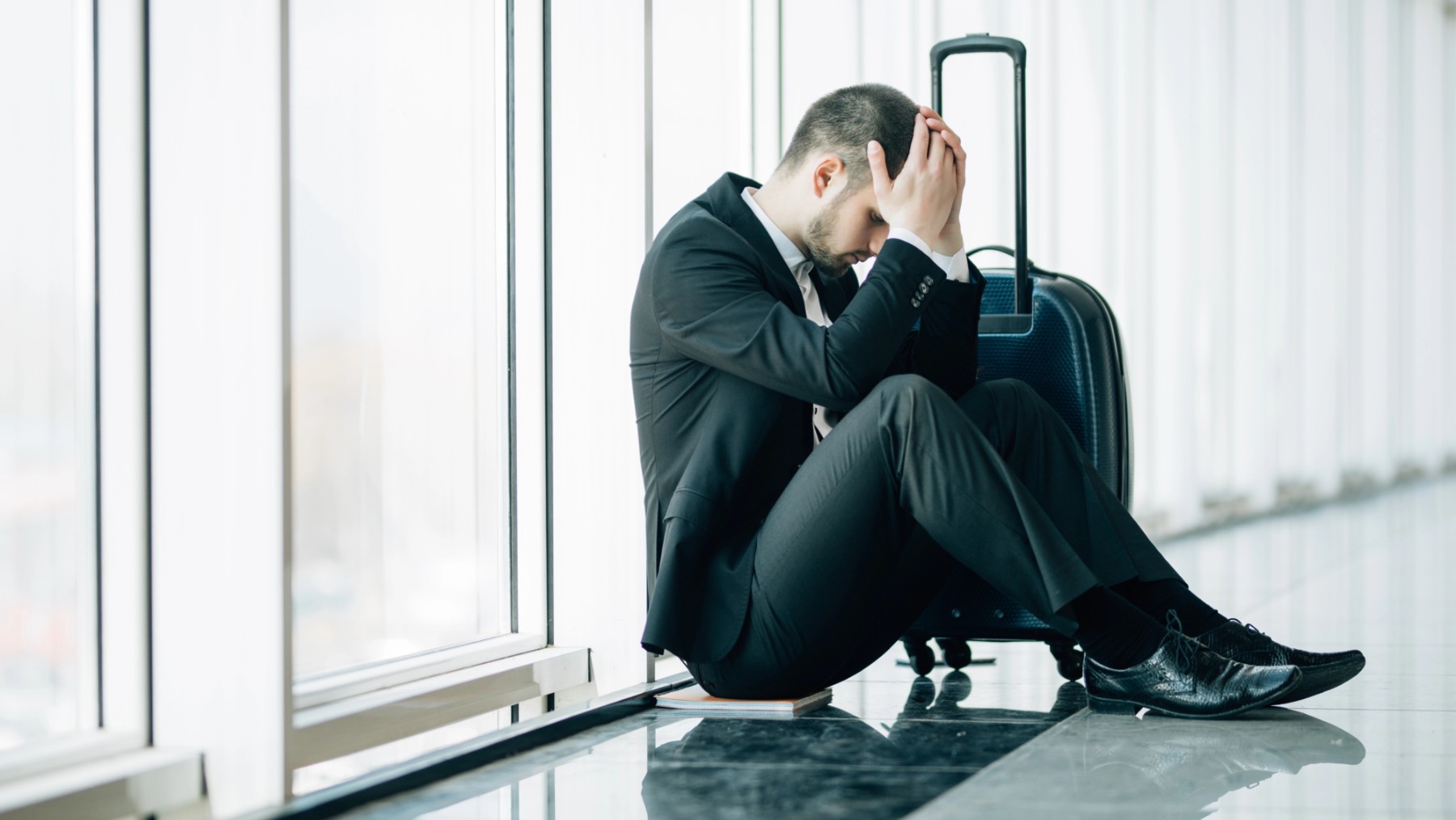 Un hombre en un aeropuerto sufriendo superar el jet lag.