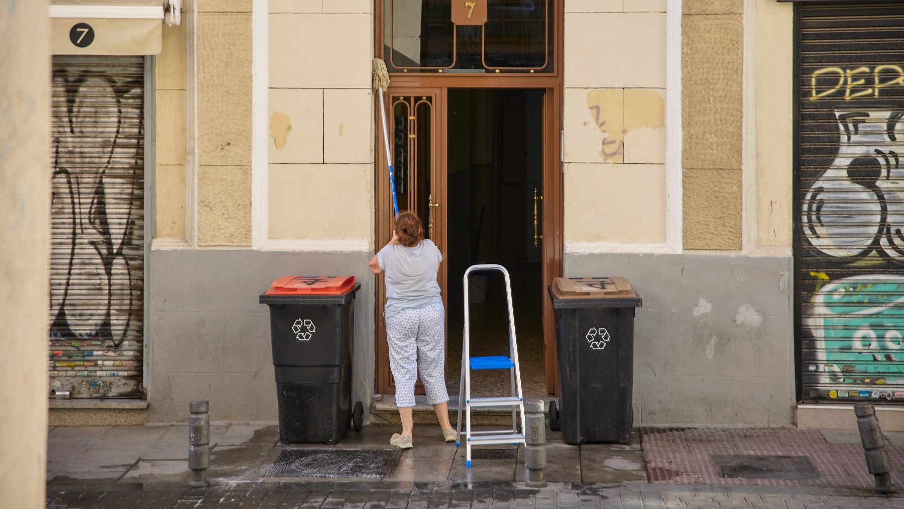 Una mujer limpia la puerta de un edificio. (EP)