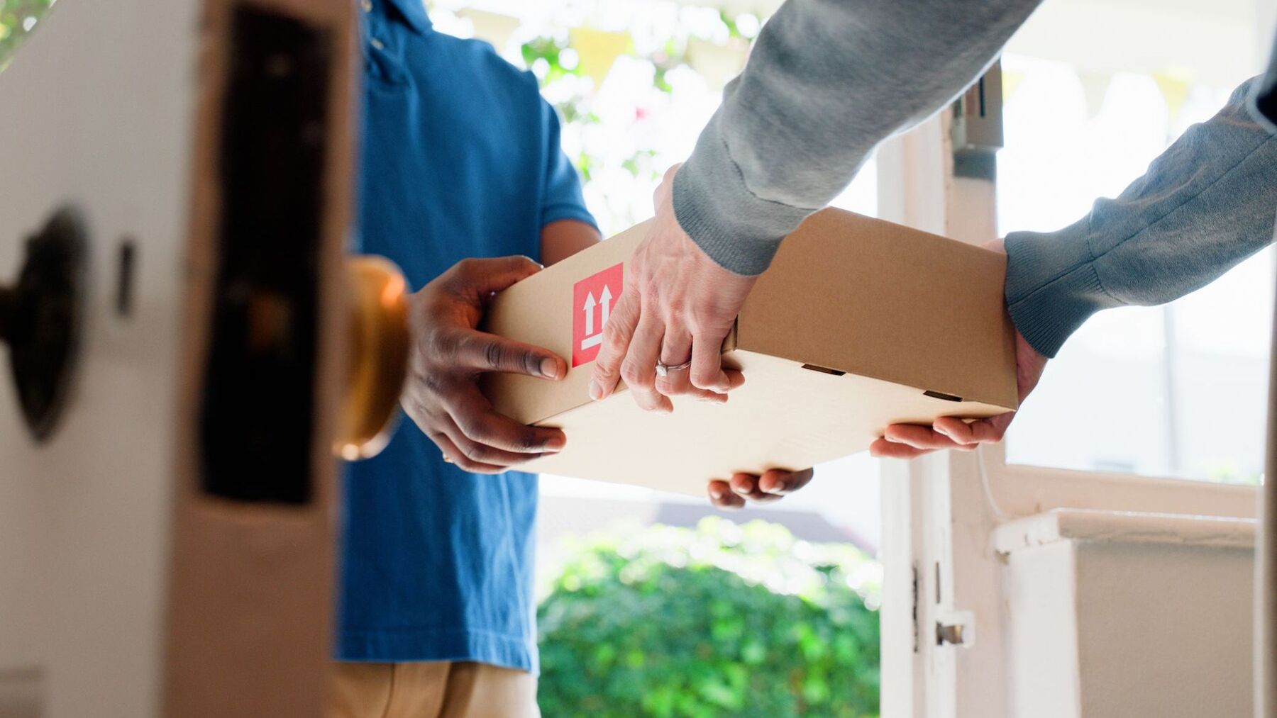 Hands, box and delivery man at front door in home with client, services and shipping for commercial product. People, courier and cardboard package for supply chain, logistics or distribution at house