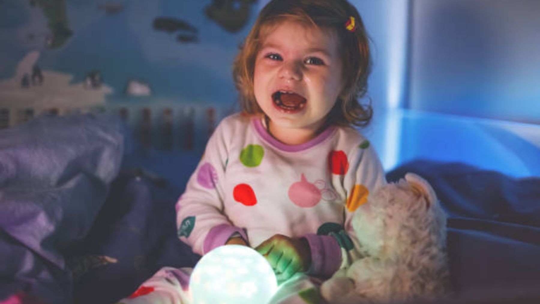 Niña llora en su cama por la noche.