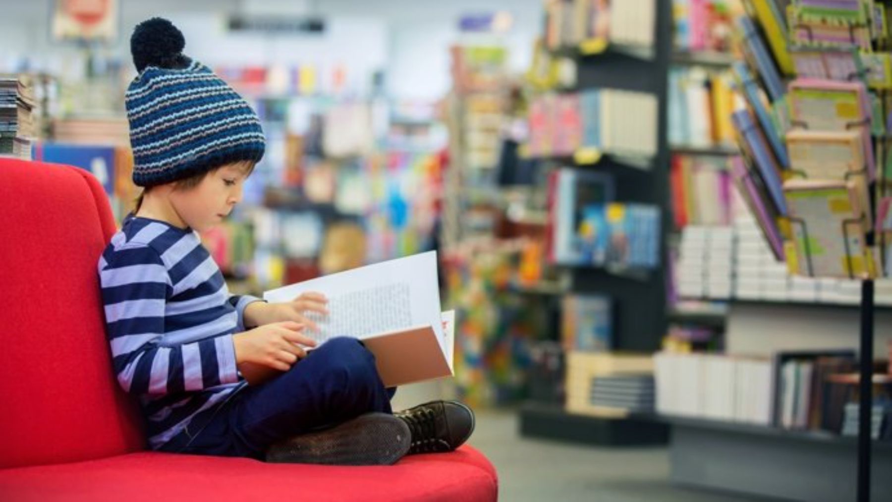 Niño leyendo libro en una librería.