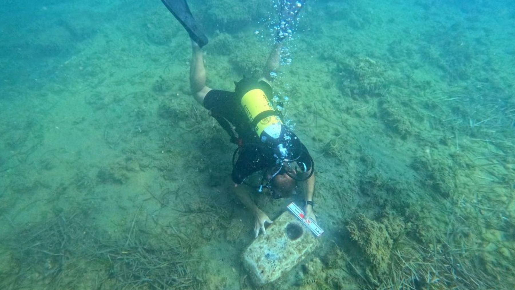 Un arqueólogo examinando una de las anclas de piedra encontradas junto al barco hundido. Foto: Superintendencia del Mar / Universidad de Udine