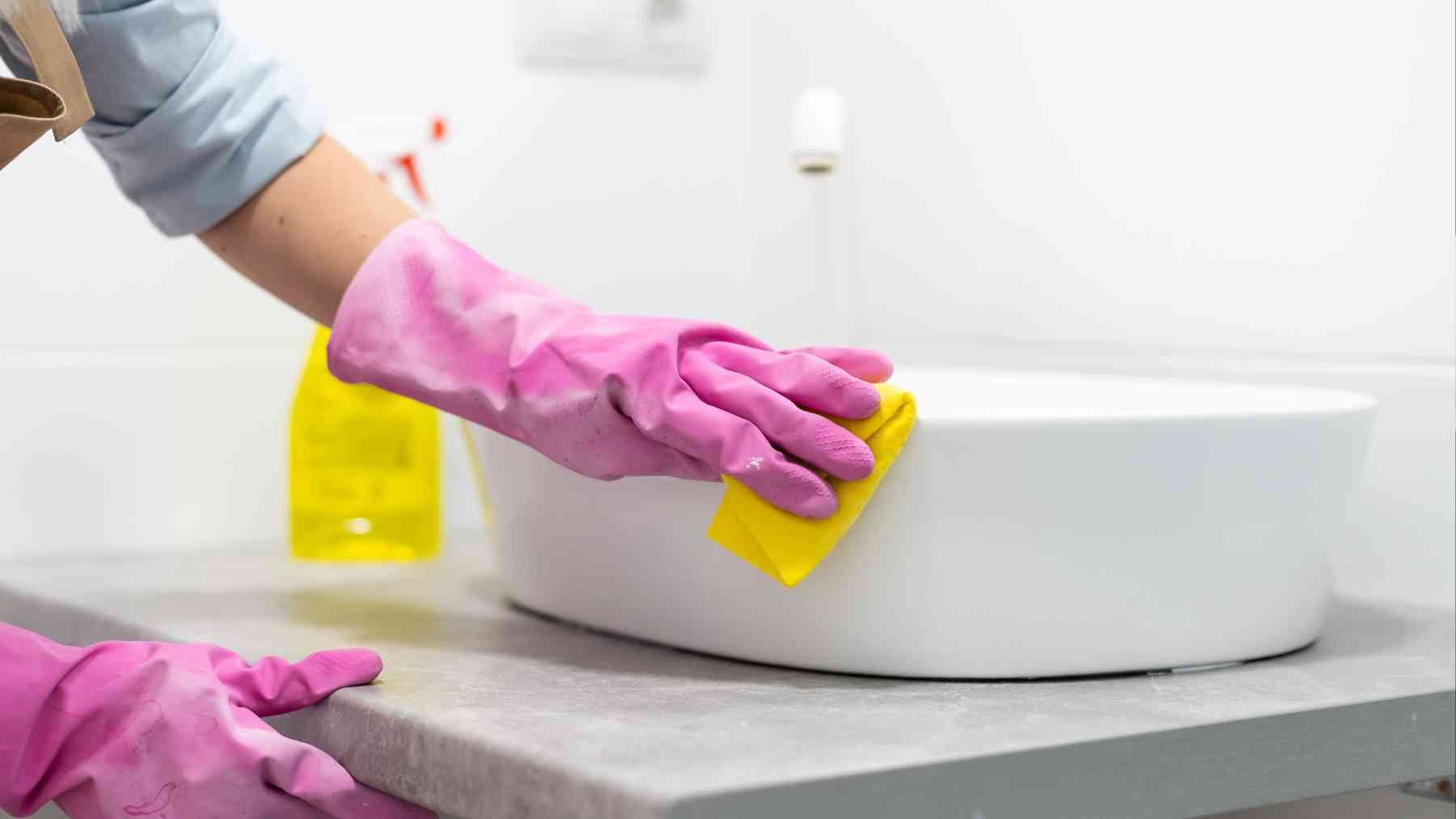 Una persona limpiando el lavabo.