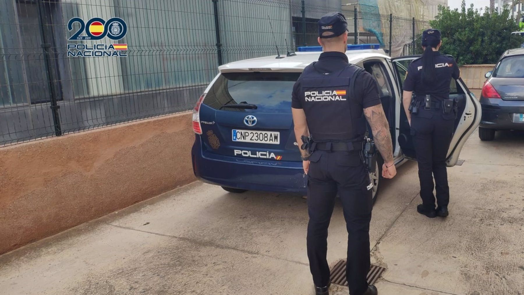 Agentes de la Policía Nacional frente a un coche patrulla.