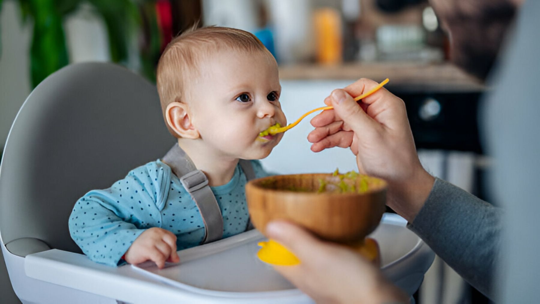 Un padre da de comer al bebé con una cuchara.