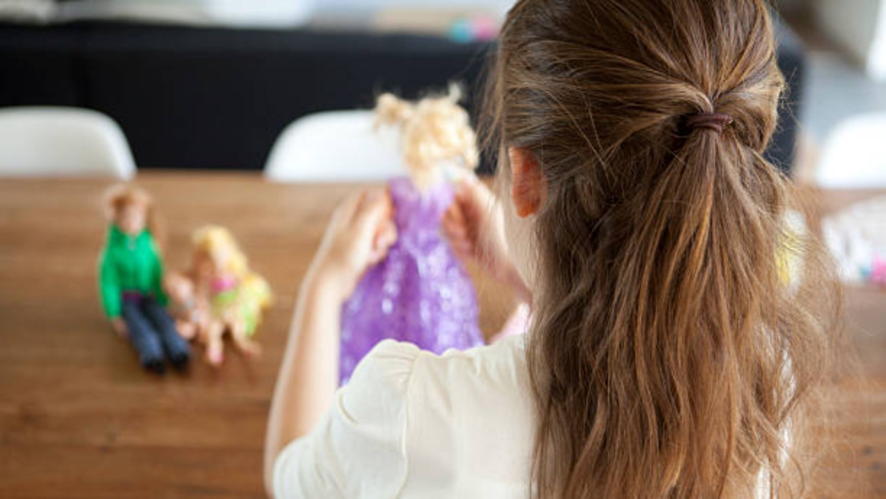 Niña jugando con muñecas.