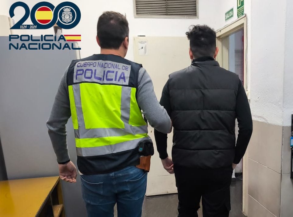 El detenido por maltrato infantil custodiado por un agente de la Policía Nacional.