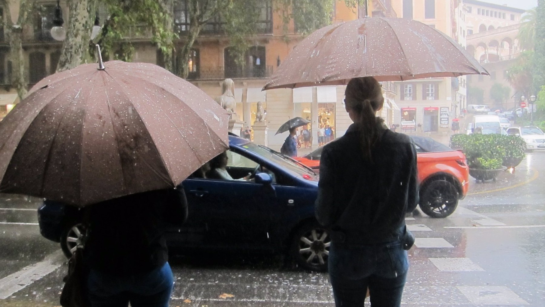 Dos personas con paraguas para cubrirse de la fuerte lluvia en el Paseo del Borne de Palma. (Europa Press)