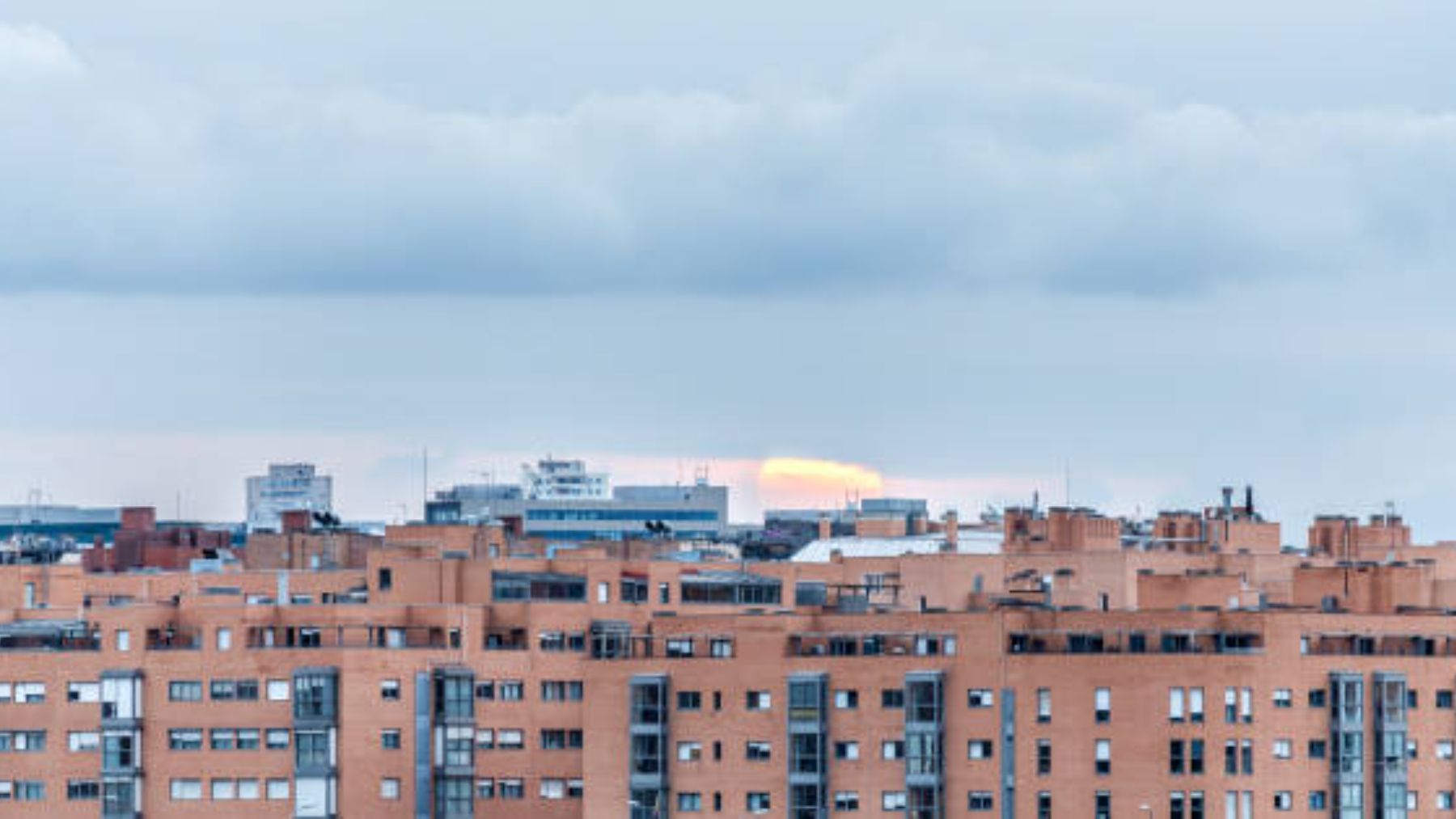 Sol saliendo por detrás de unos edificios.