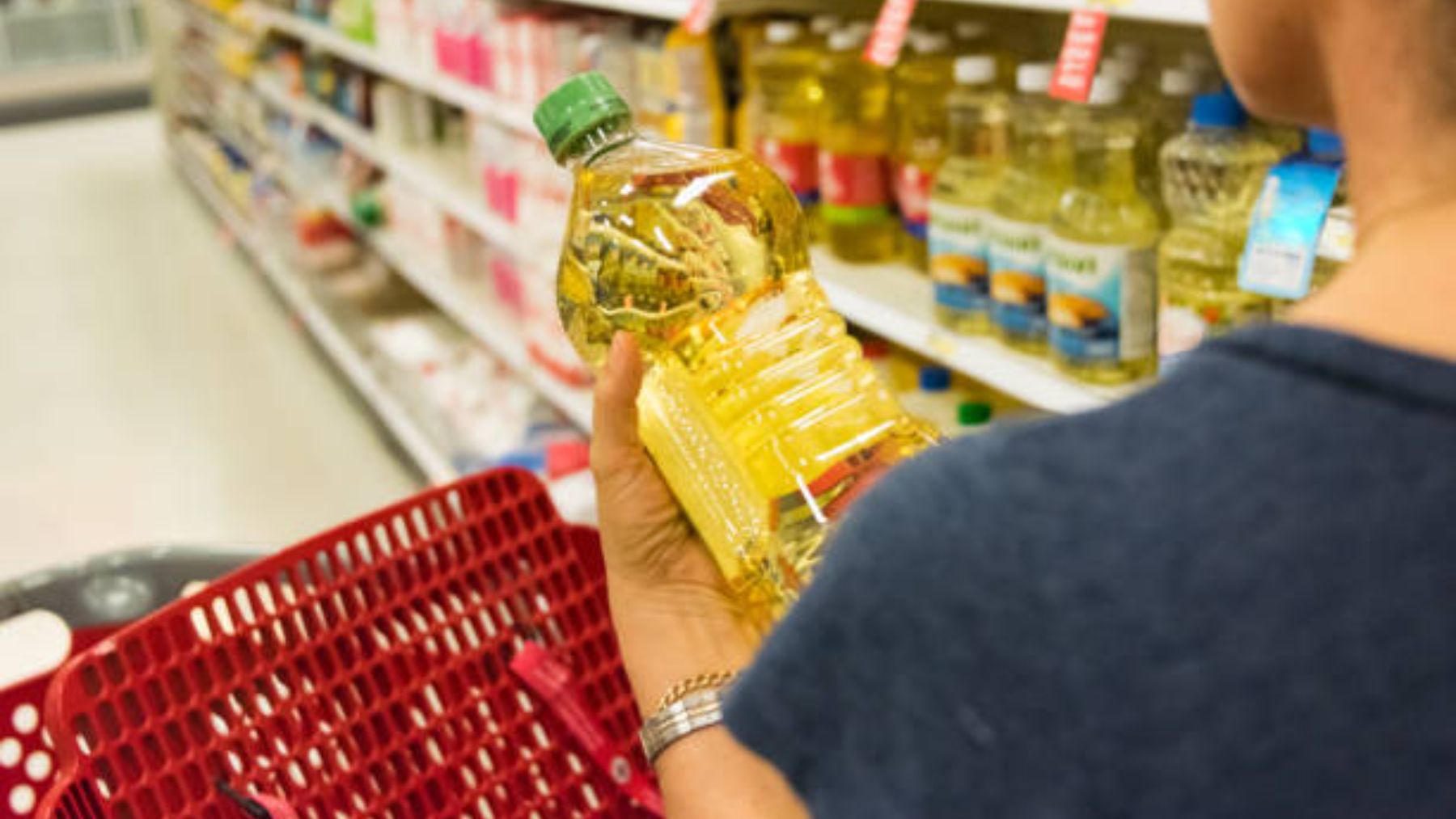 Persona en un supermercado con una botella de aceite.