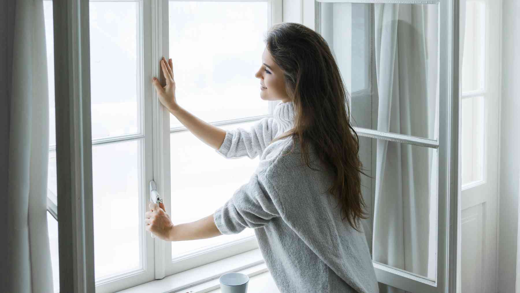 Una mujer abriendo la ventana.