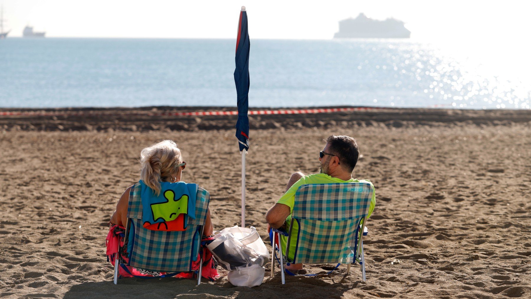 Dos personas sentadas en la playa de Málaga. (EP)