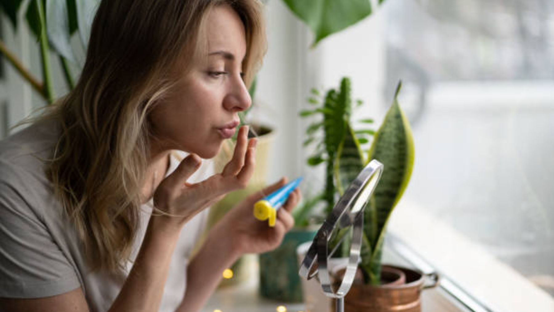 Mujer aplicándose producto en los labios.