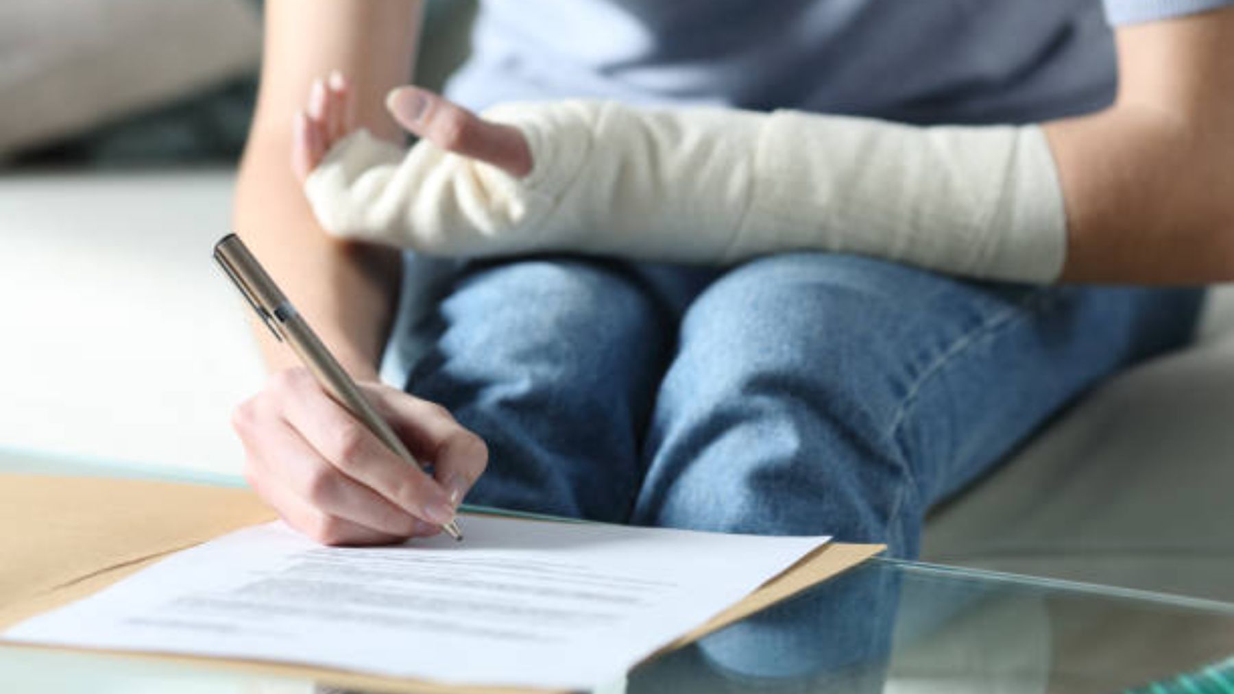 Mujer con el brazo vendado que firma un documento.