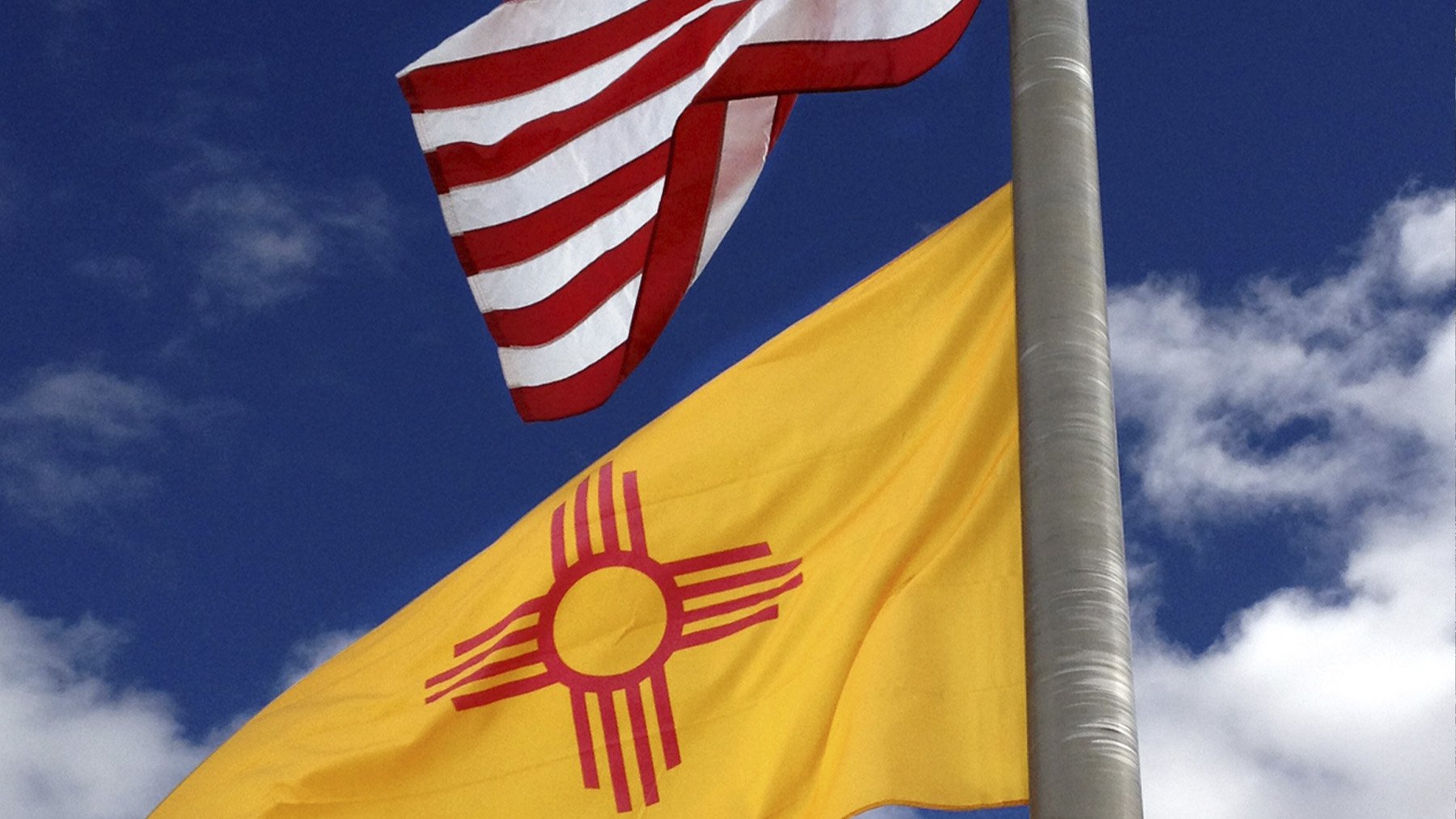 Bandera de Nuevo México flameando junto a la de Estados Unidos. Foto: SteveStrummer en Wikimedia Commons.