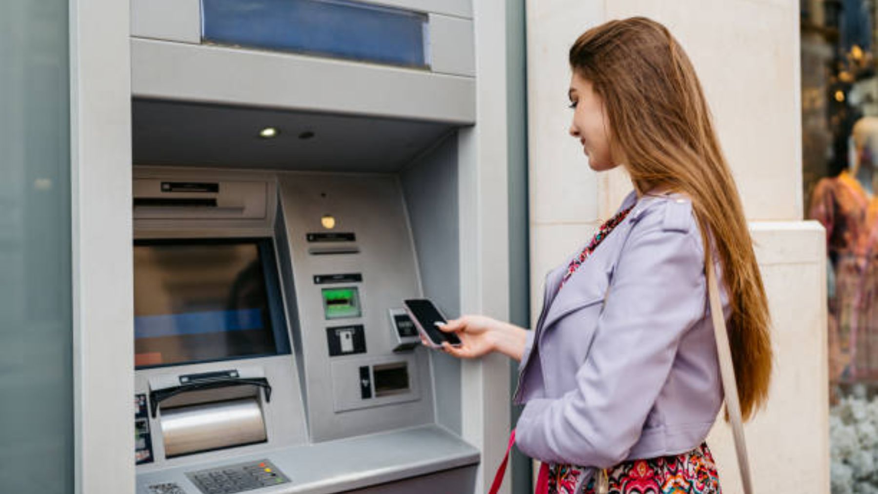 Joven sacando dinero de un cajero.