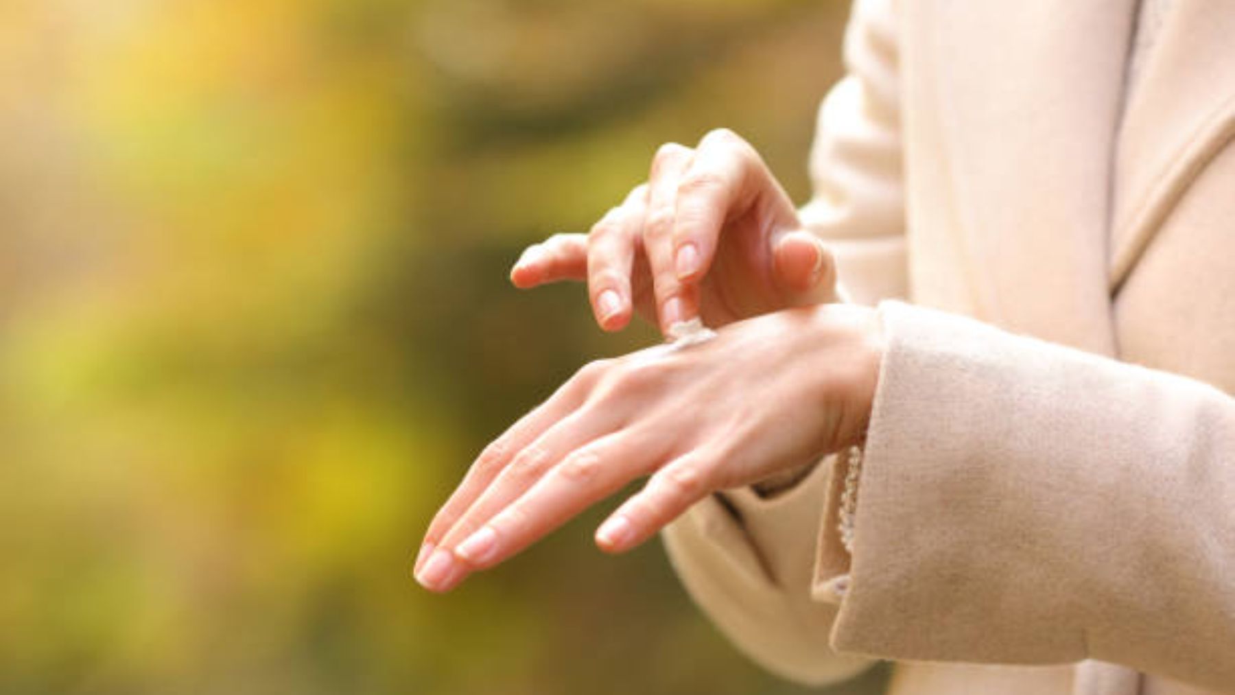 Mujer aplicándose crema en las manos.