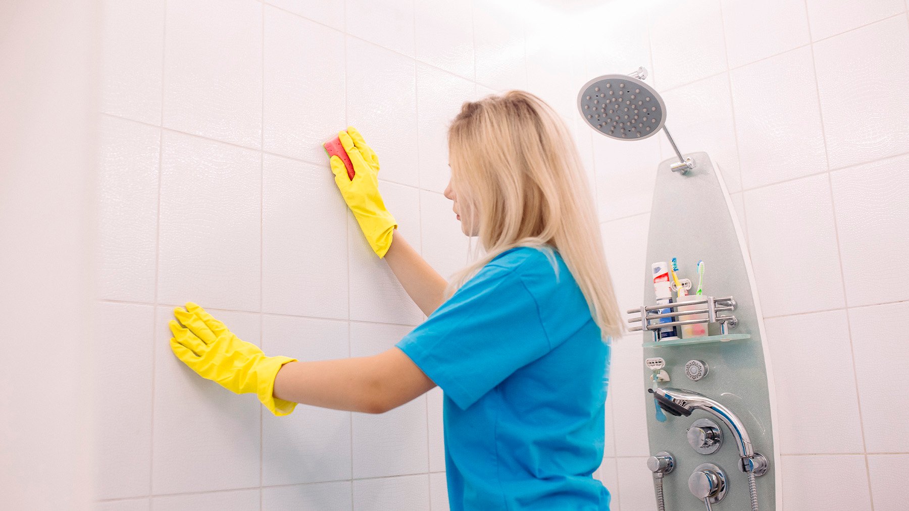 Mujer limpiando las baldosas del baño. Foto: Freepik.