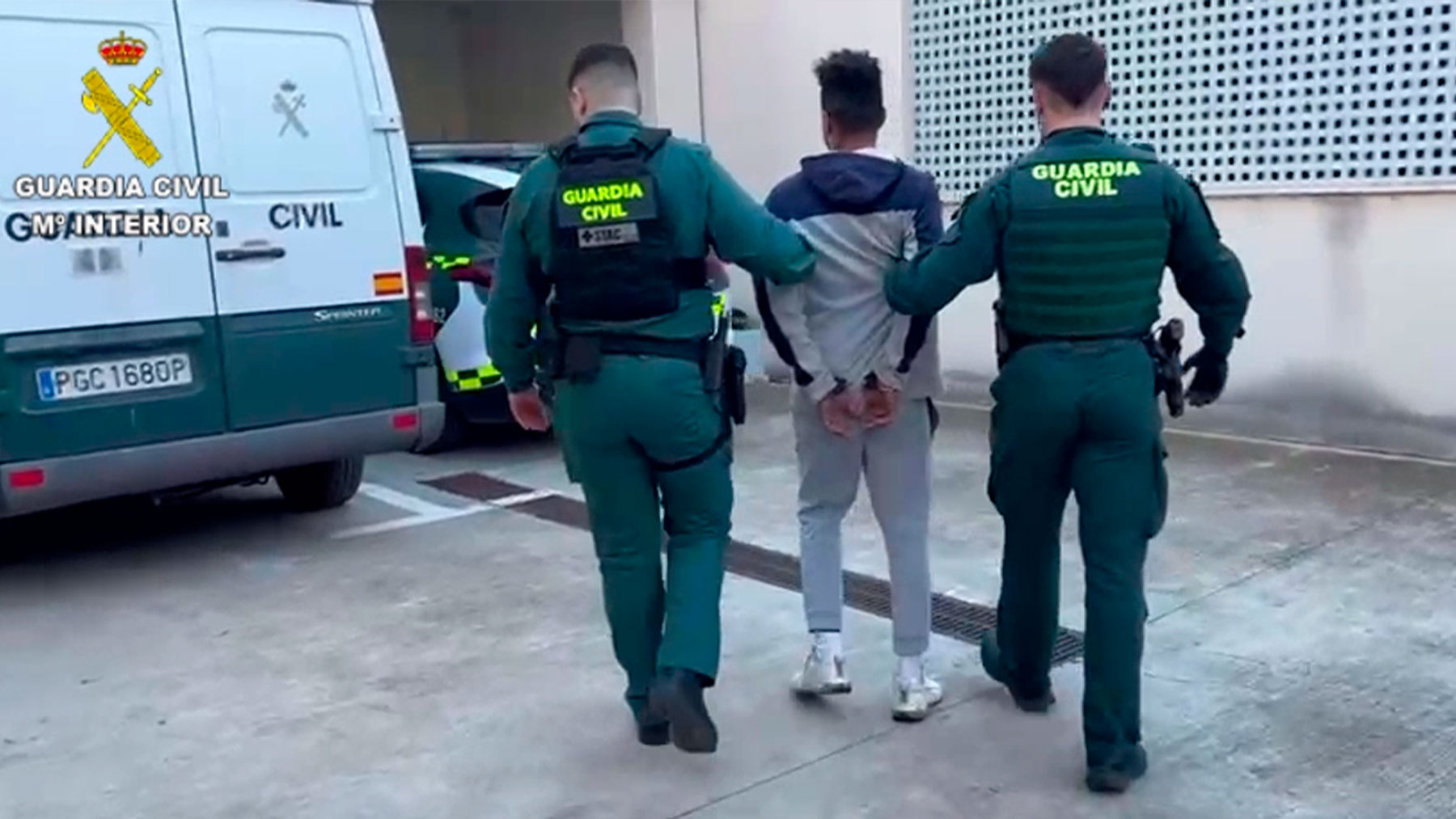 Dos agentes de la Guardia Civil llevan esposado a uno de los ladrones.