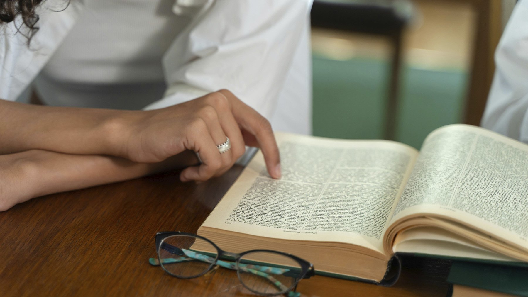 Persona buscando palabras en el diccionario. Foto: Pexels.