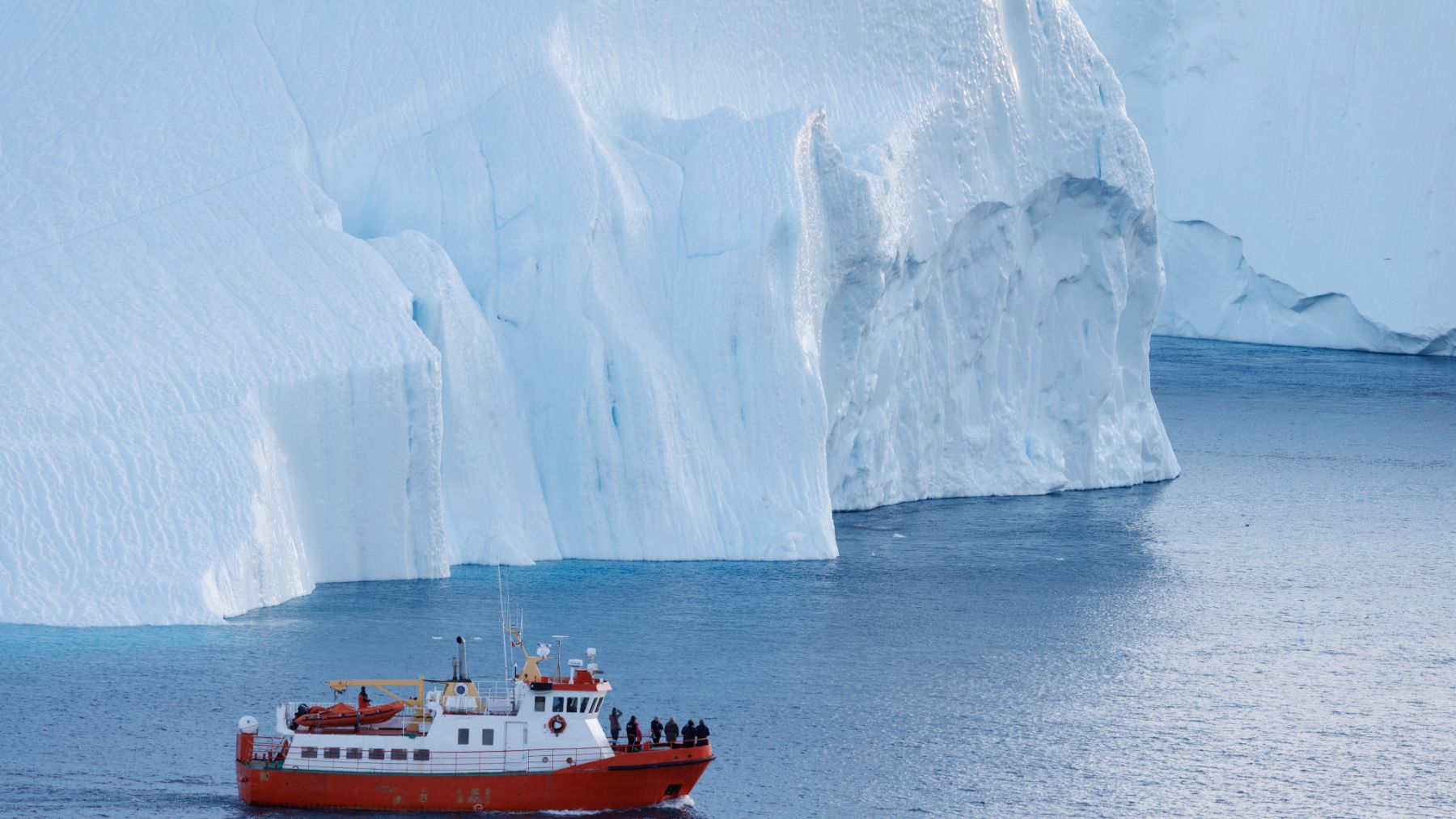 Una embarcación navegando cerca de grandes icebergs en la costa de Groenlandia