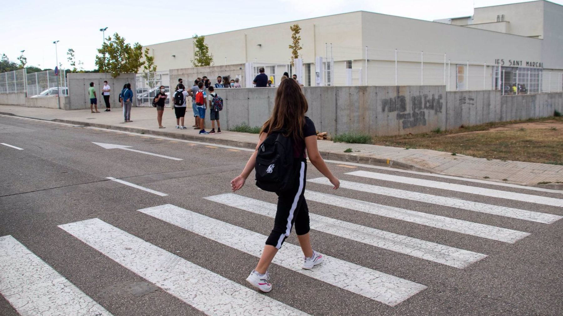 Una alumna cruza el paso de cebra para llegar a su colegio.
