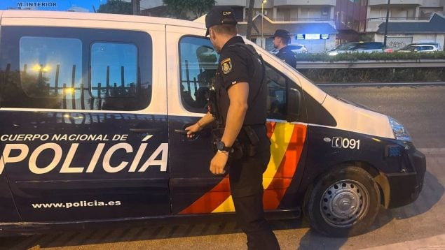 Un agente de Policía junto a su vehículo.