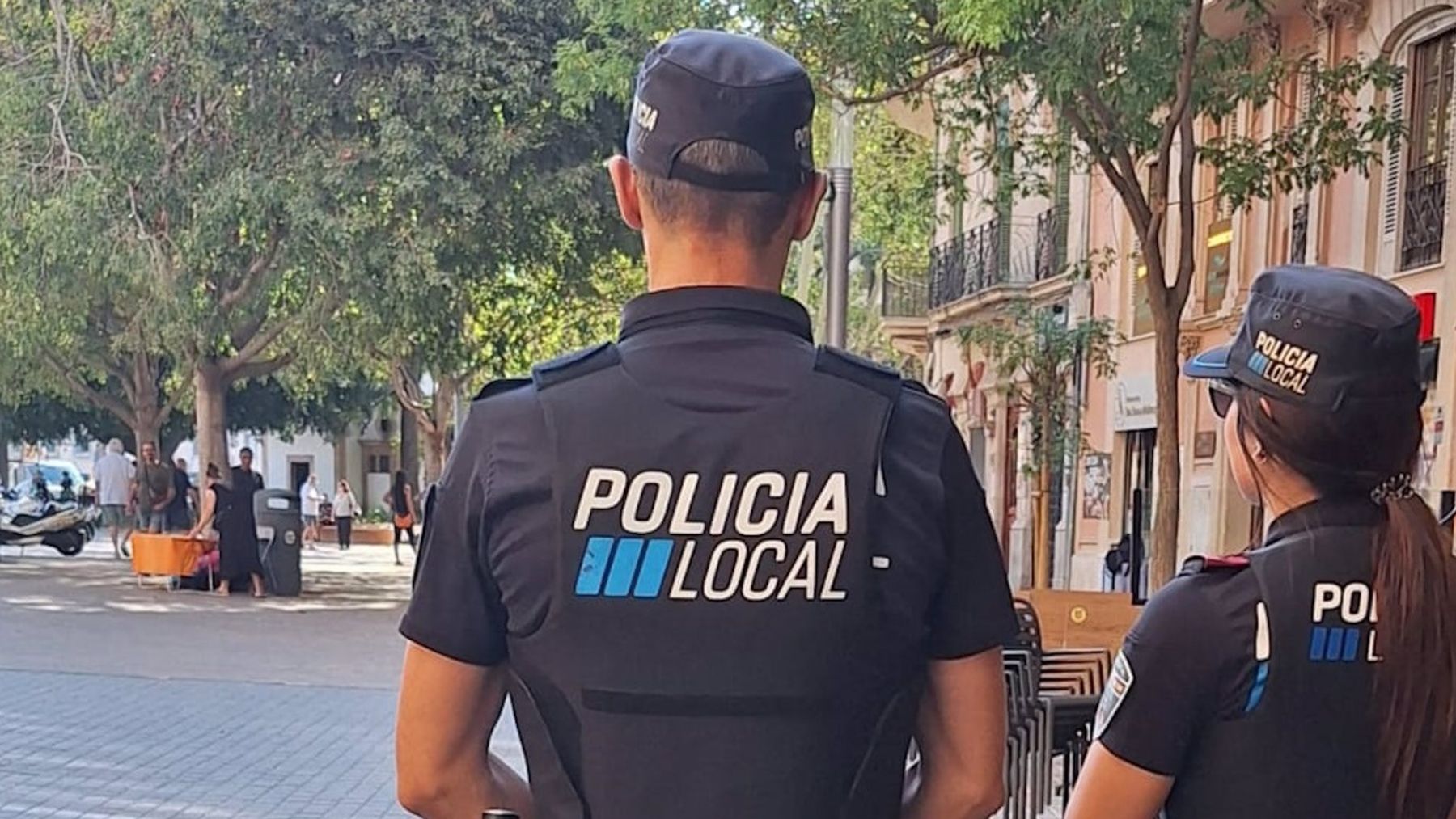 Dos agentes de la Policía Local, de espaldas, en la plaza de España de Palma.