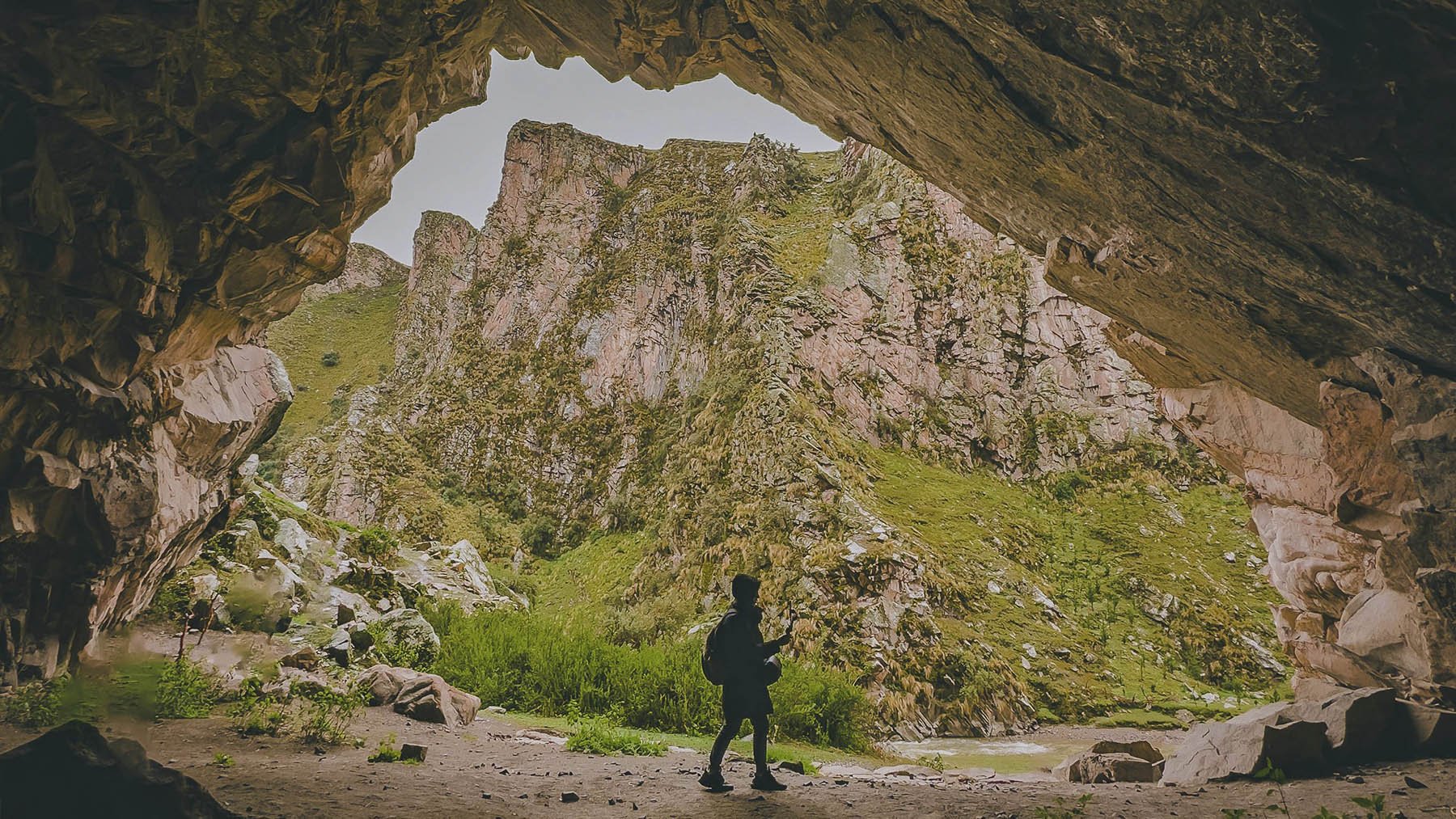 Hombre recorriendo un sendero bajo una cueva. Foto: Pexels.